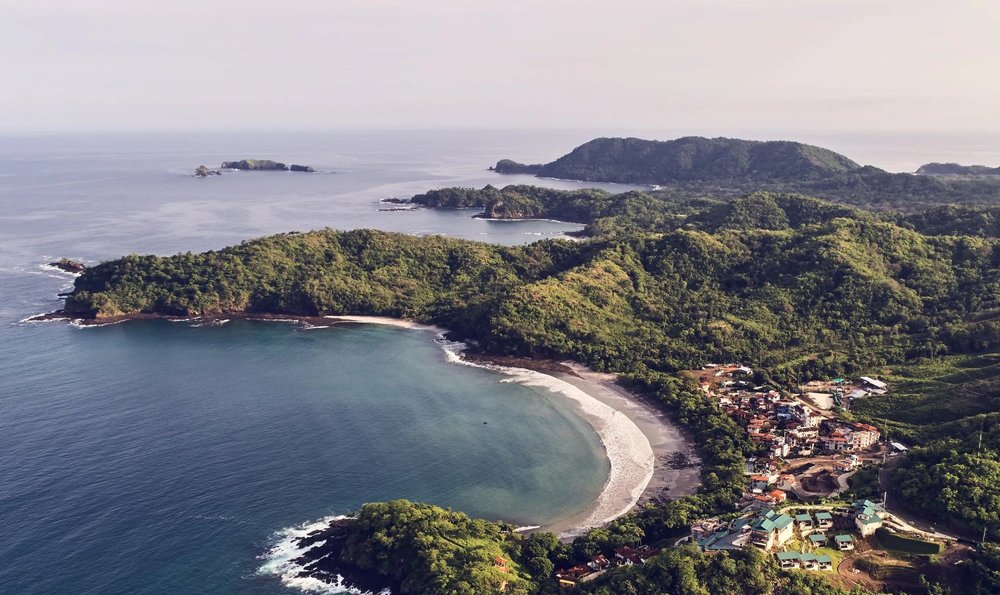 Aerial view of a crescent bay and forested headlands on a Pacific coast