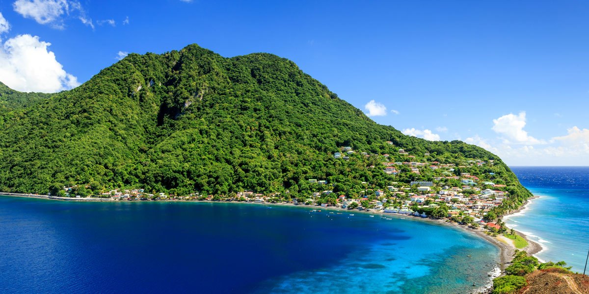 Aerial view of a village on a narrow isthmus between deep and turquoise sea.