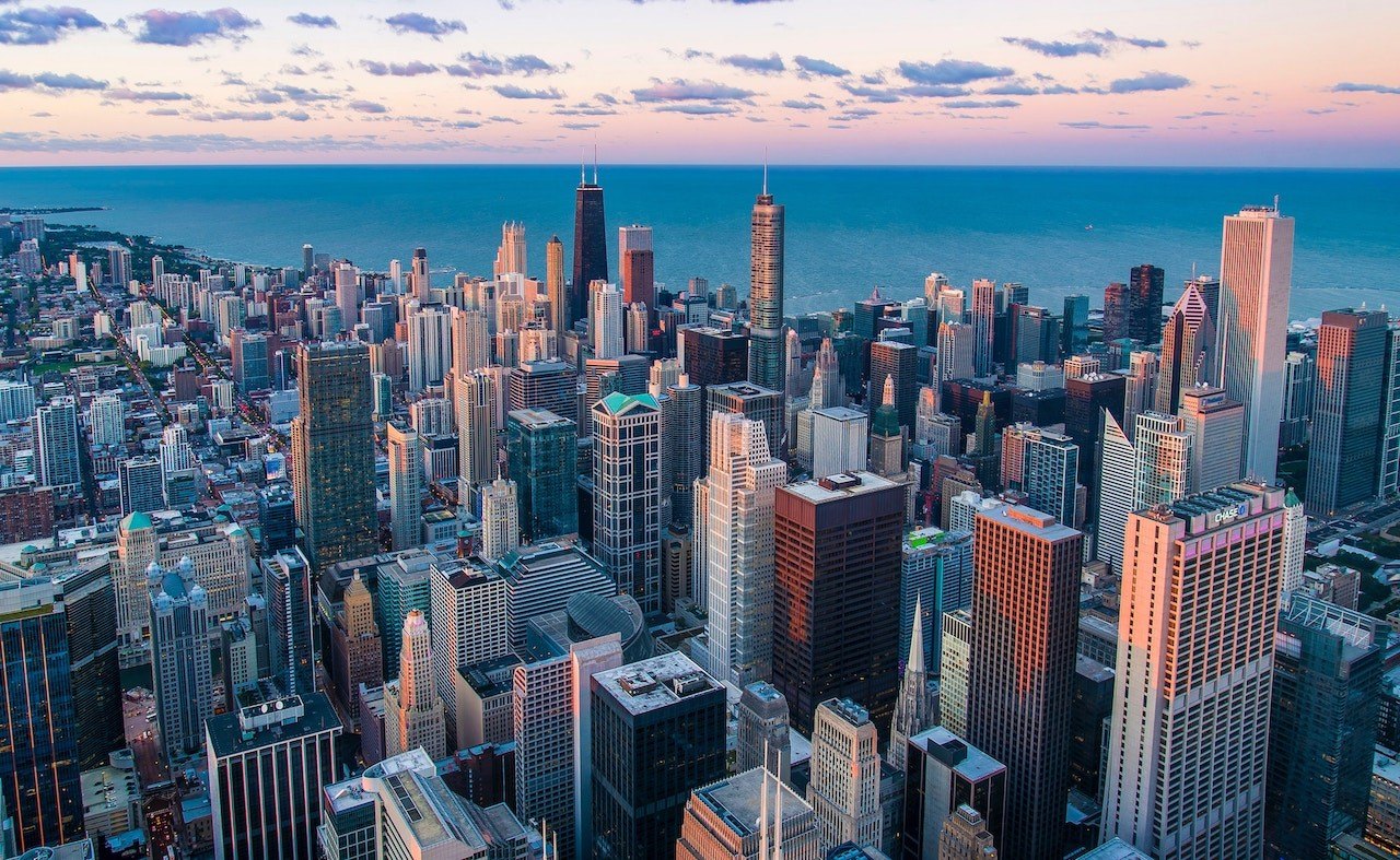 Aerial view of a downtown skyline meeting a large body of water at dusk