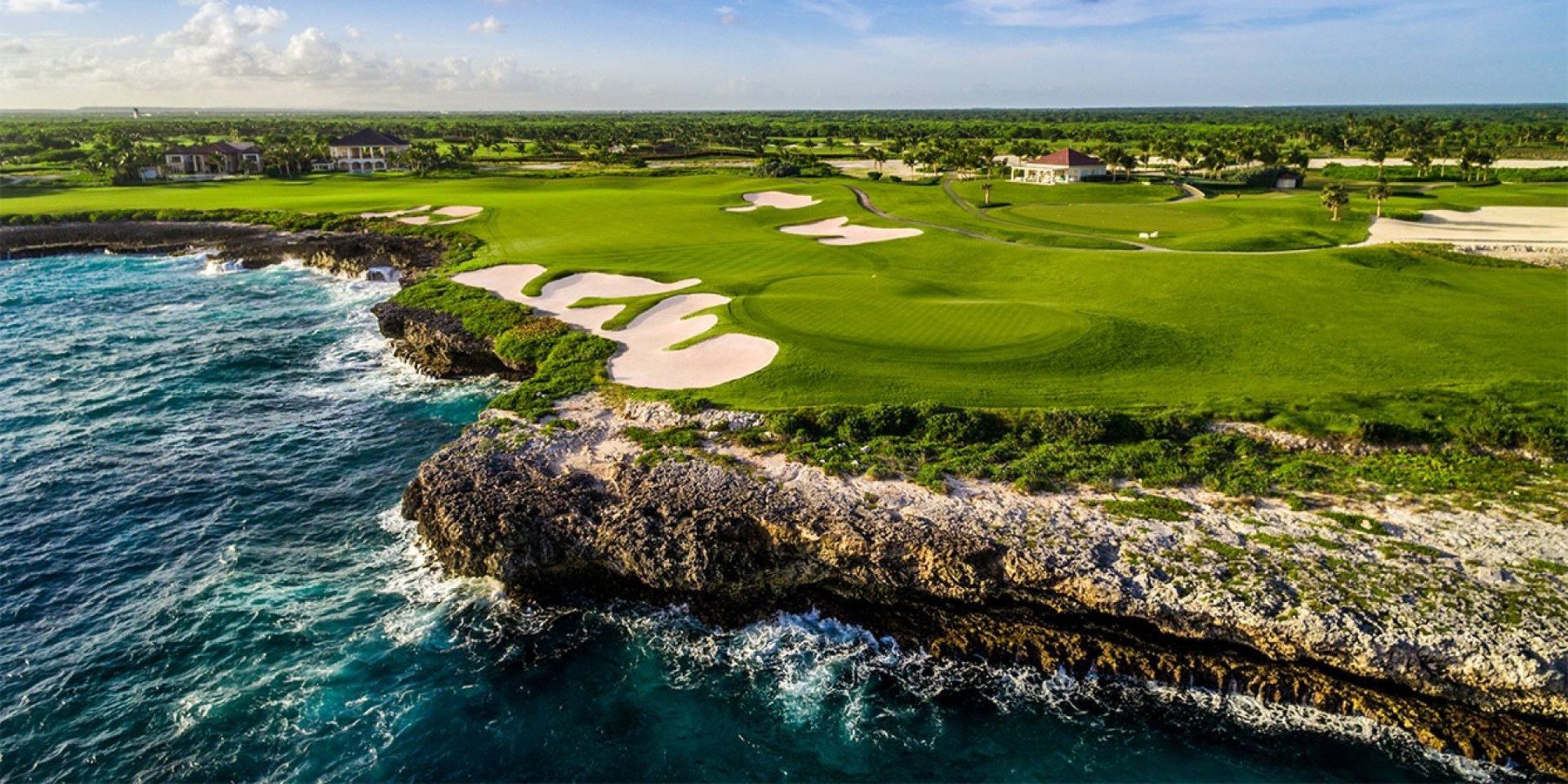 Aerial view of a manicured golf fairway ending at a rugged rocky coastline.