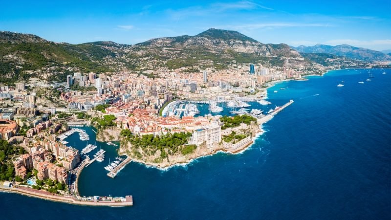 Aerial view of a hillside coastal city with two crowded yacht harbours