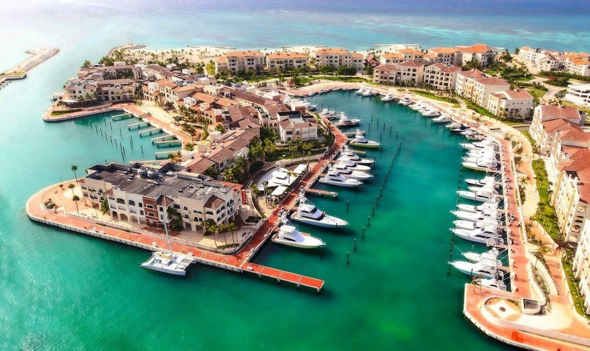 Aerial view of a marina with rows of motor yachts and waterfront buildings.