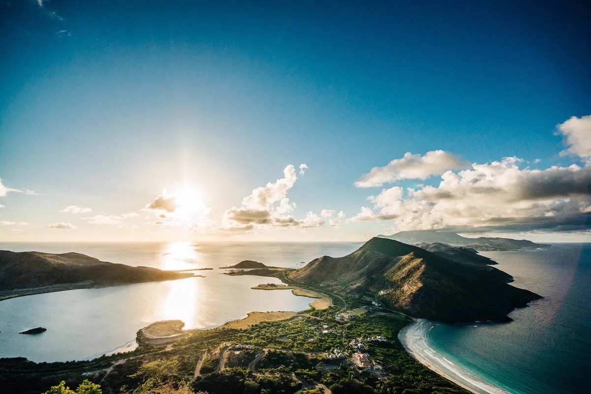 Aerial view of a narrow green peninsula between two bays at sunset