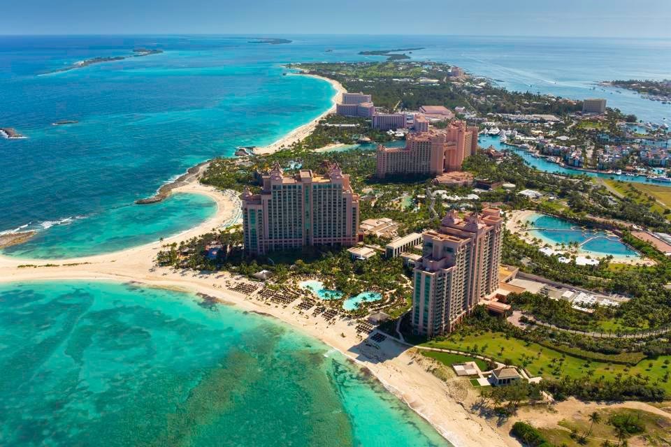 Aerial view of pink resort towers on a palm-fringed peninsula beside turquoise water