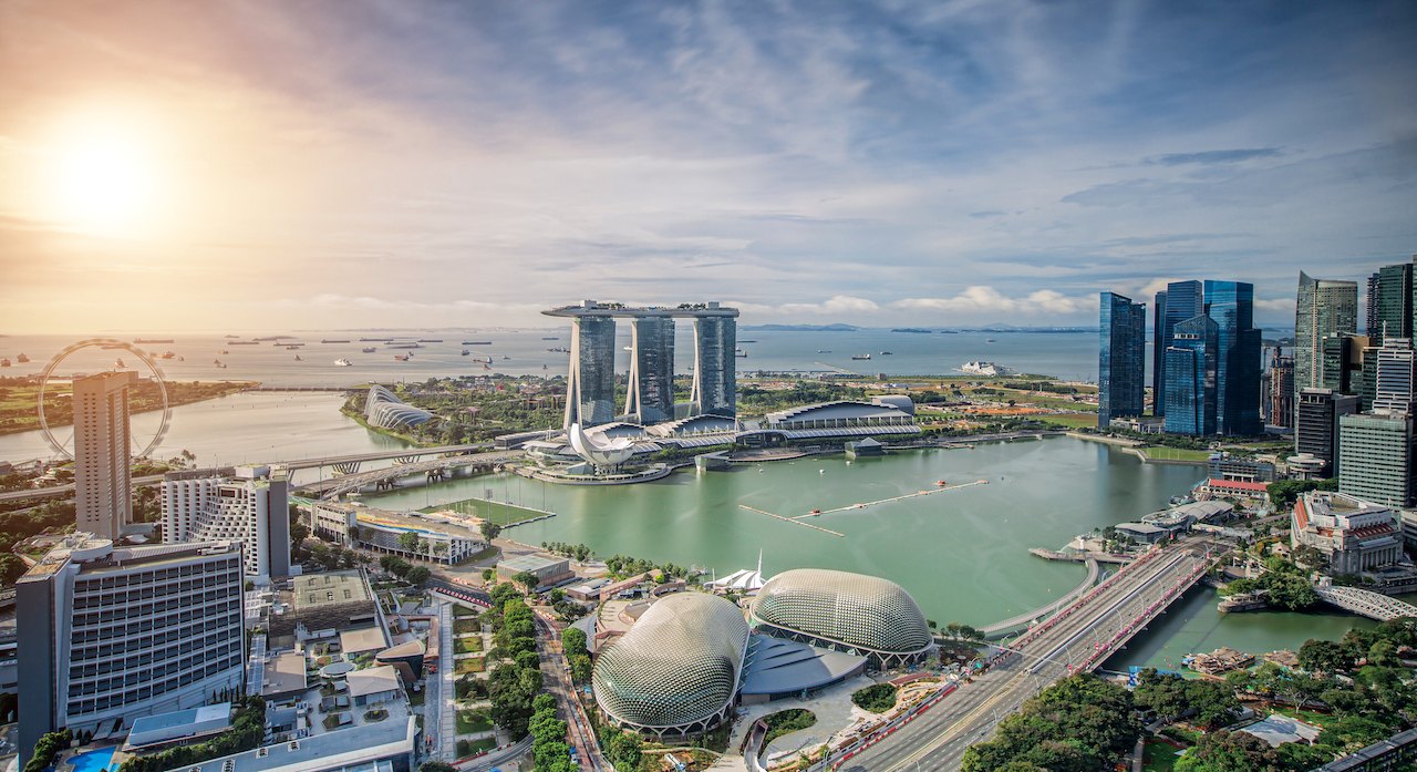 Aerial view of a waterfront financial district with towers ringing a calm bay