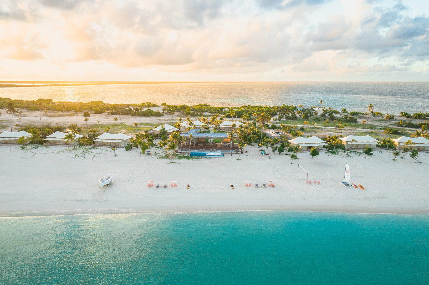 Sunset aerial of Barbuda Ocean Club's beach village, white sand and shallow turquoise water
