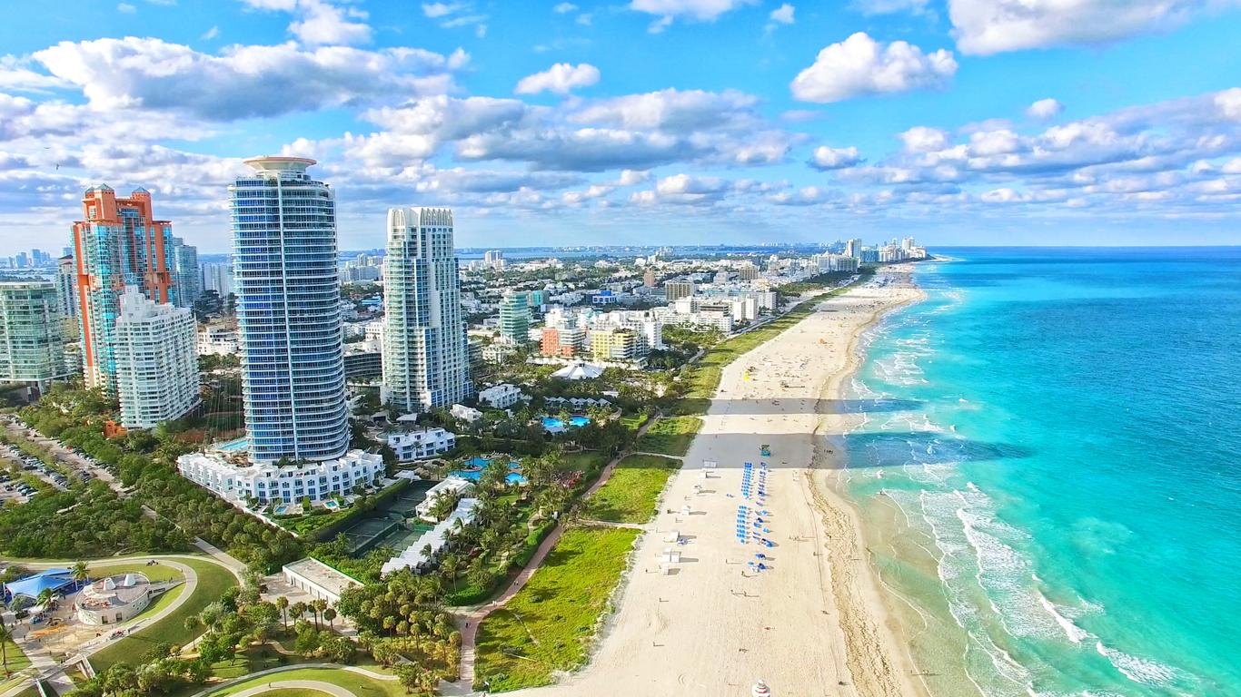 Aerial view of high-rise towers beside a wide sand beach and turquoise sea