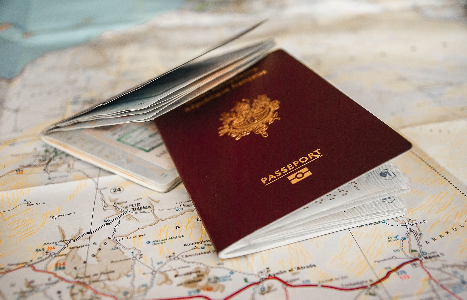 Burgundy passport lying open on a folded topographic road map