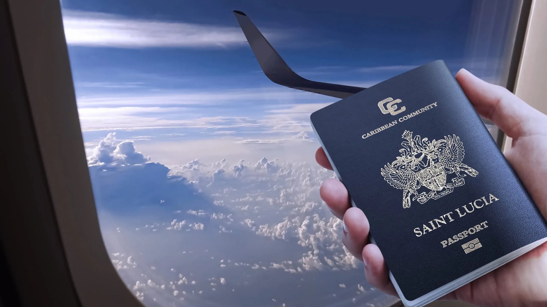 Hand holding a dark blue Caribbean Community passport beside an aircraft window above clouds