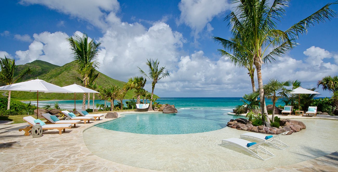 Free-form infinity pool and loungers above the beach at Christophe Harbour, Southeast Peninsula, St Kitts