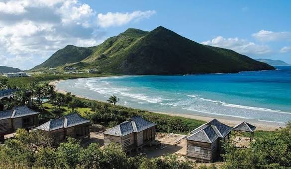 Timber beach cabanas above the crescent bay and headland at Christophe Harbour, St Kitts