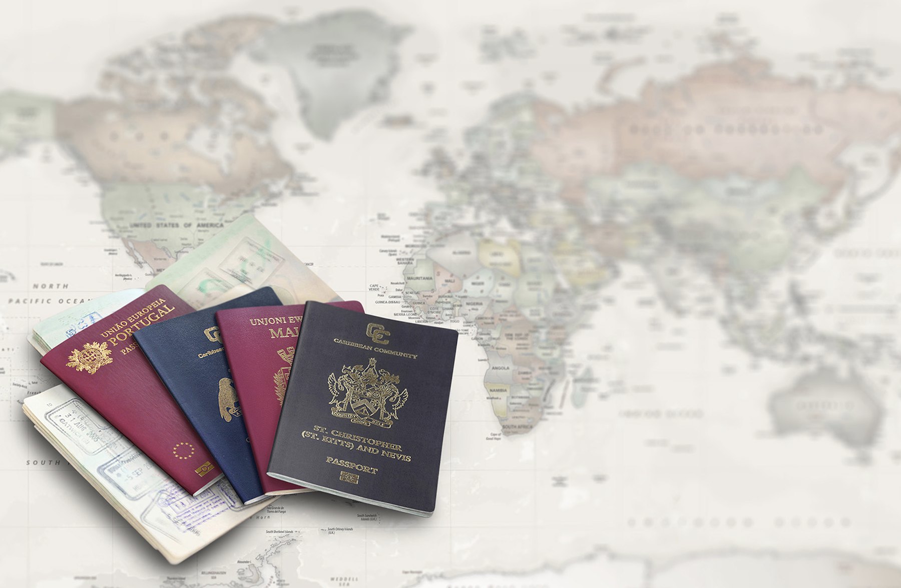 Five passports of different colours fanned across a faded world map background