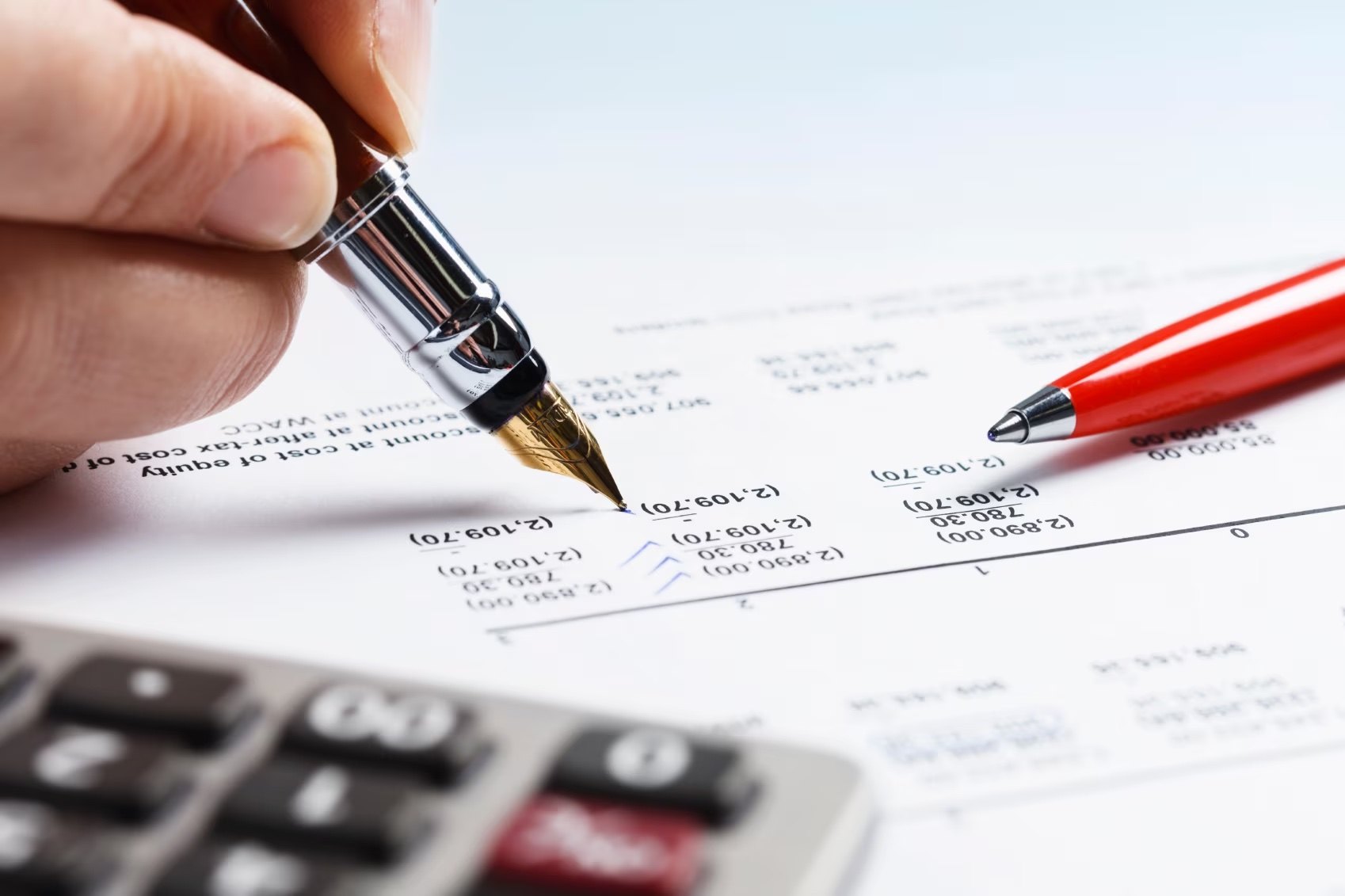 A fountain pen and a calculator resting on a discounted cash-flow statement