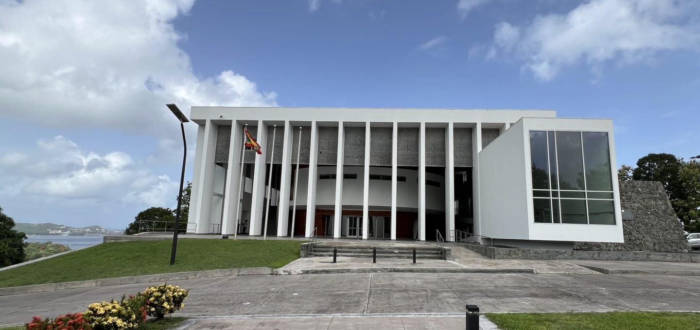 The colonnaded front of Grenada's Houses of Parliament with the Grenadian national flag flying