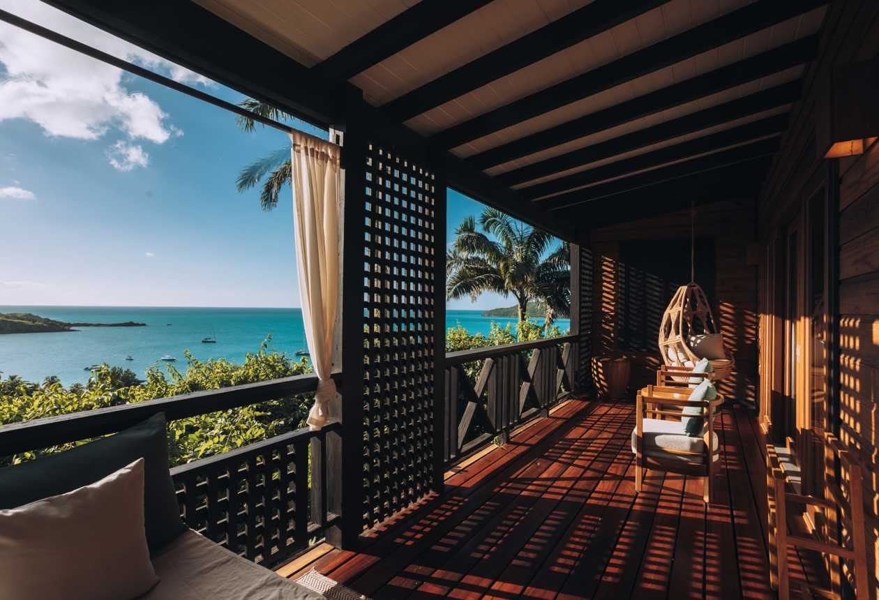Timber suite veranda with hanging chair and sea view at Hermitage Bay, Antigua