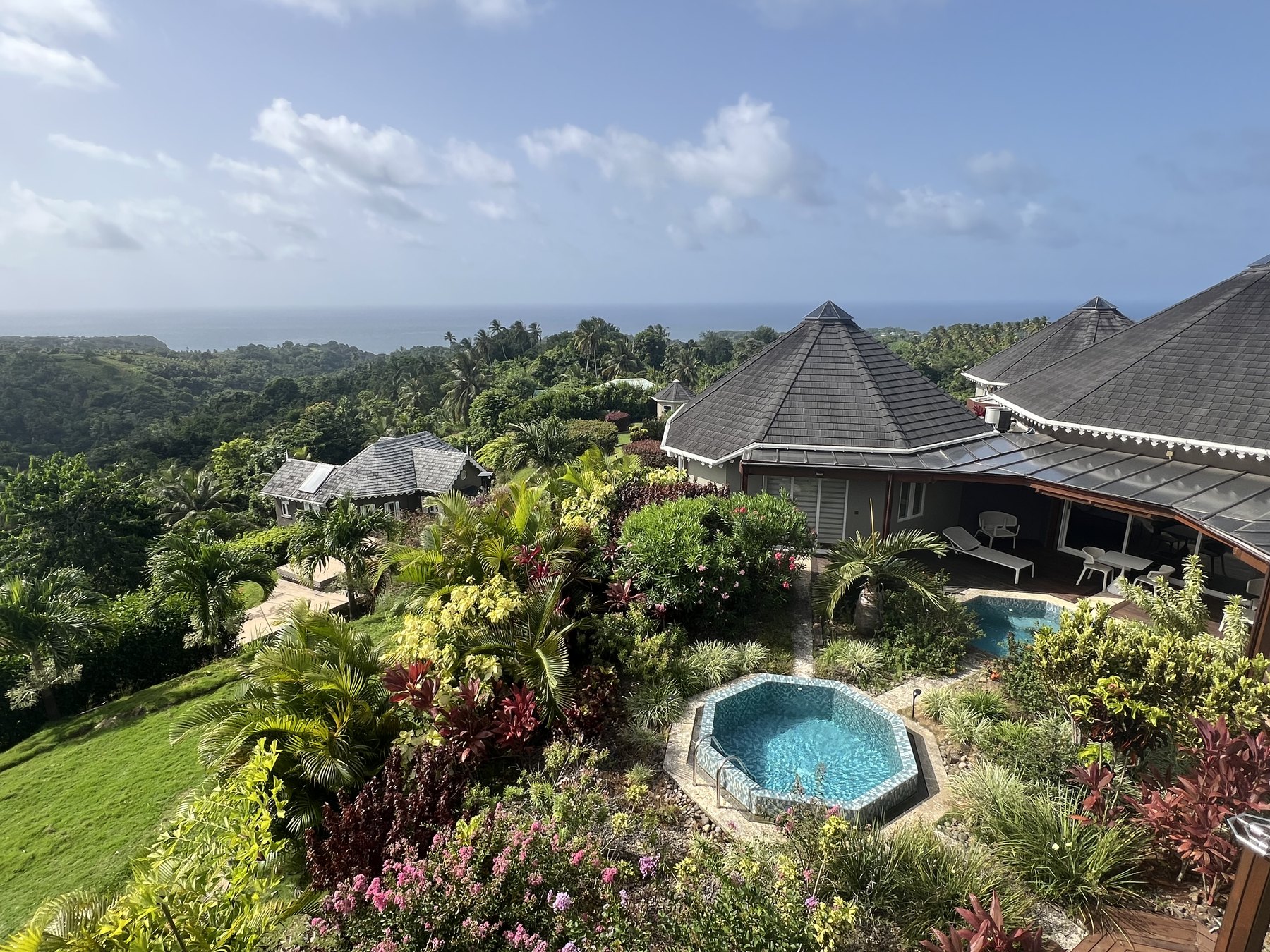Hilltop houses with plunge pools and flowering gardens overlooking distant ocean.