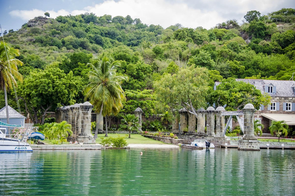 Row of weathered stone colonnade pillars beside calm dockyard water and a Georgian building
