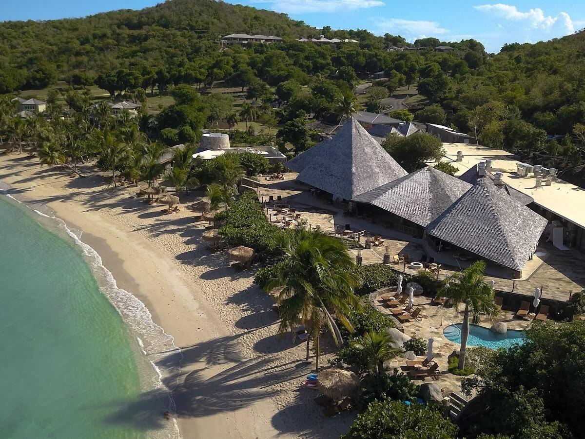 Aerial of the crescent white-sand beach and shingled pavilions, Rosewood Little Dix Bay