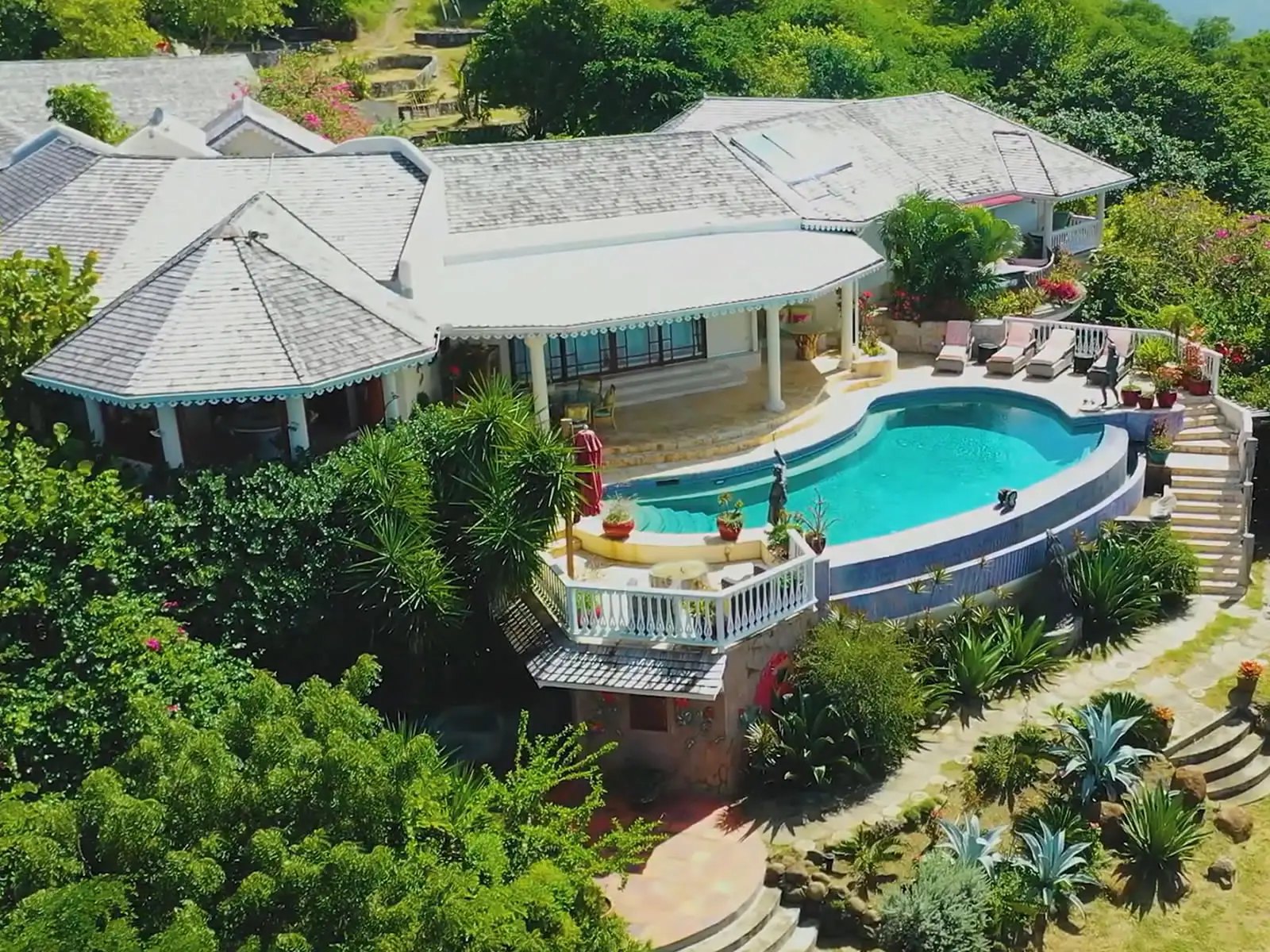 Hillside villa with curved pool terrace and grey shingle roofs, Cap Estate, St. Lucia