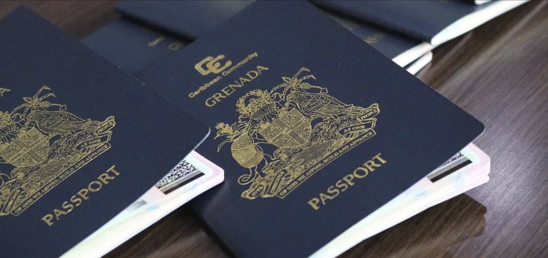 Several navy passports with identity cards tucked inside, laid on a dark desk