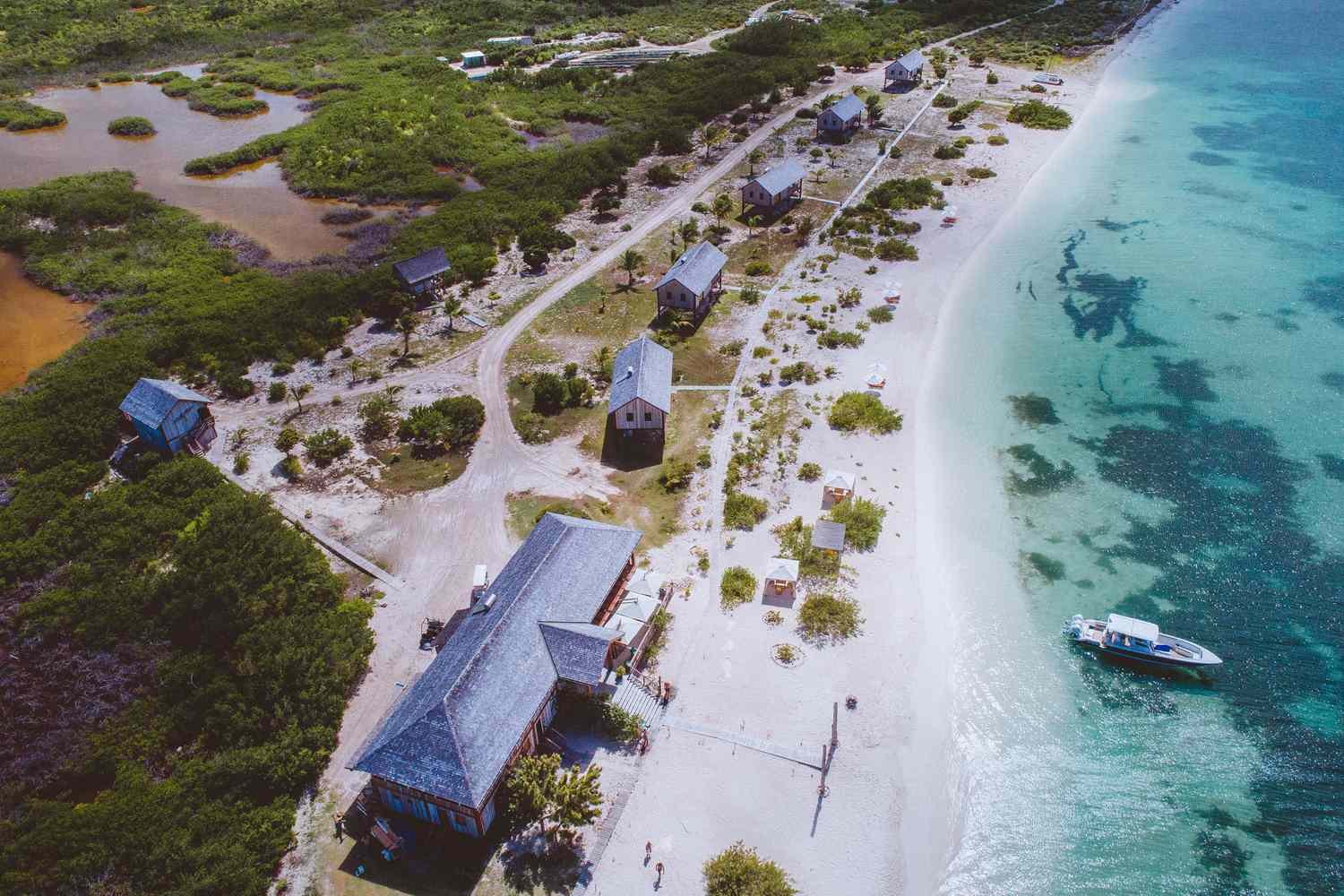 Aerial view of timber beachfront cottages, mangrove lagoon and reef water on Barbuda