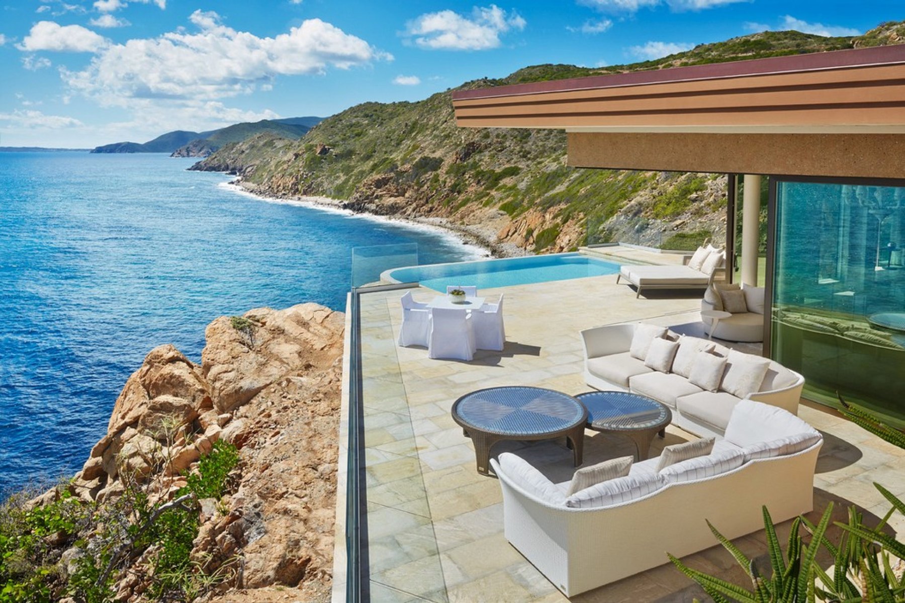 Clifftop infinity pool and terrace seating above the rocky Atlantic coast at Oil Nut Bay