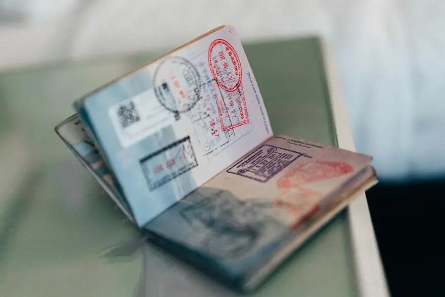 An open passport resting on a table, pages filled with coloured entry stamps