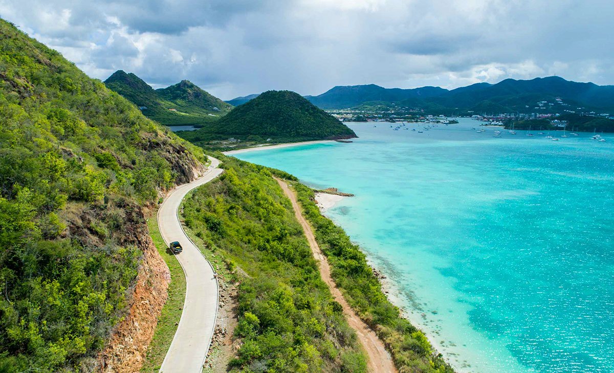 Paved coastal road winding above turquoise water on the Pearns Point peninsula, Antigua