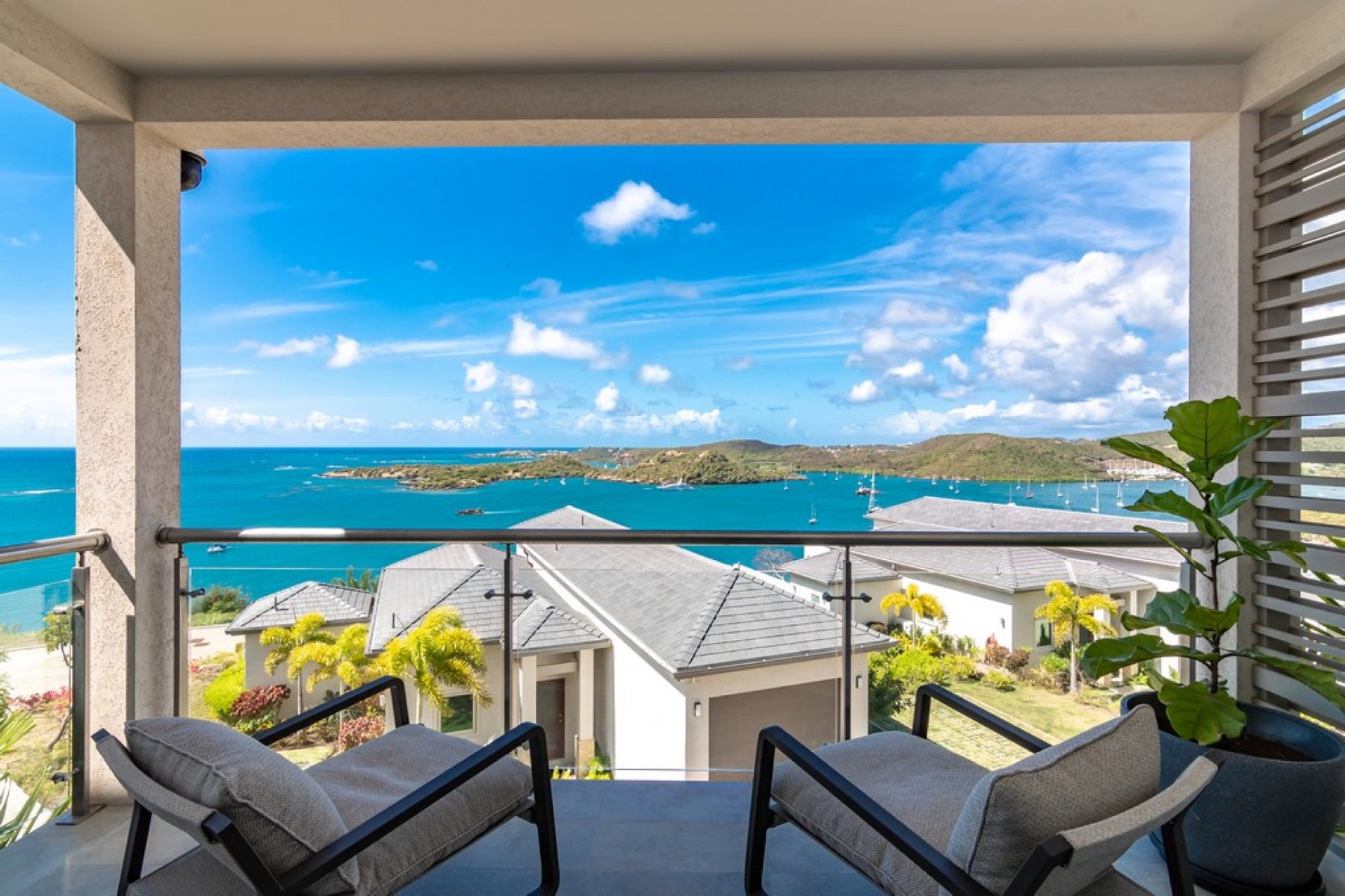 Covered terrace at The Point at Petite Calivigny framing villa rooftops and Grenada's turquoise bay
