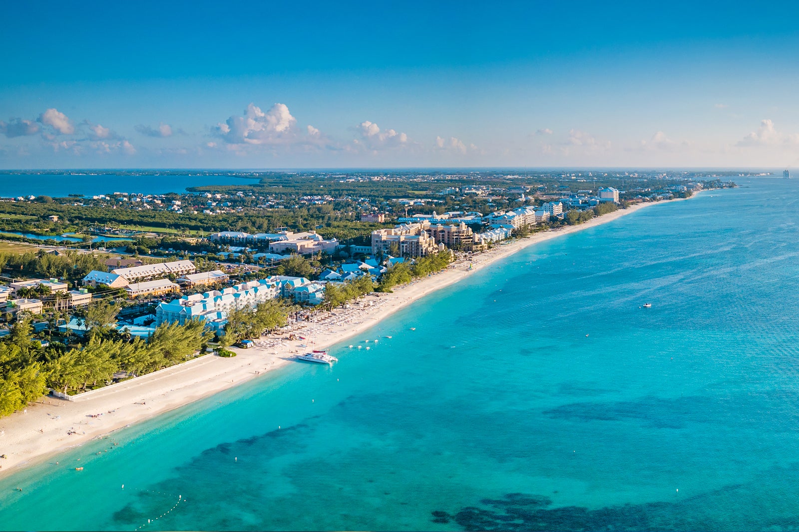 Aerial view along Seven Mile Beach, Grand Cayman — a flat strip of resorts and condominiums between turquoise sea and the North Sound