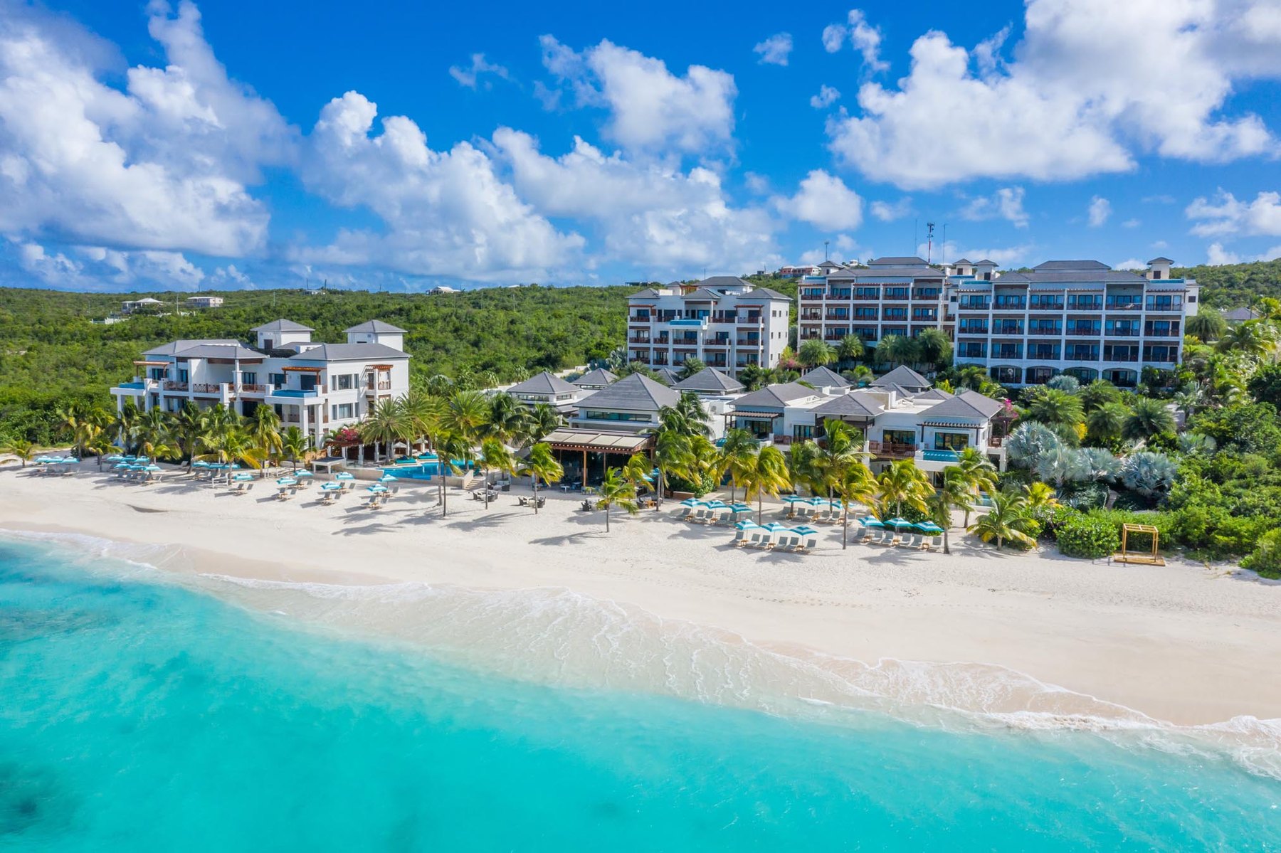 Low-rise beachfront resort buildings and shaded loungers on a white-sand Anguilla beach