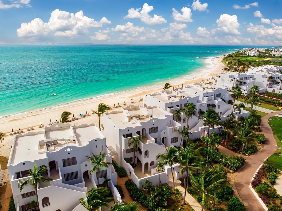 White beachfront residences above pale sand and turquoise shallows on Anguilla's south coast