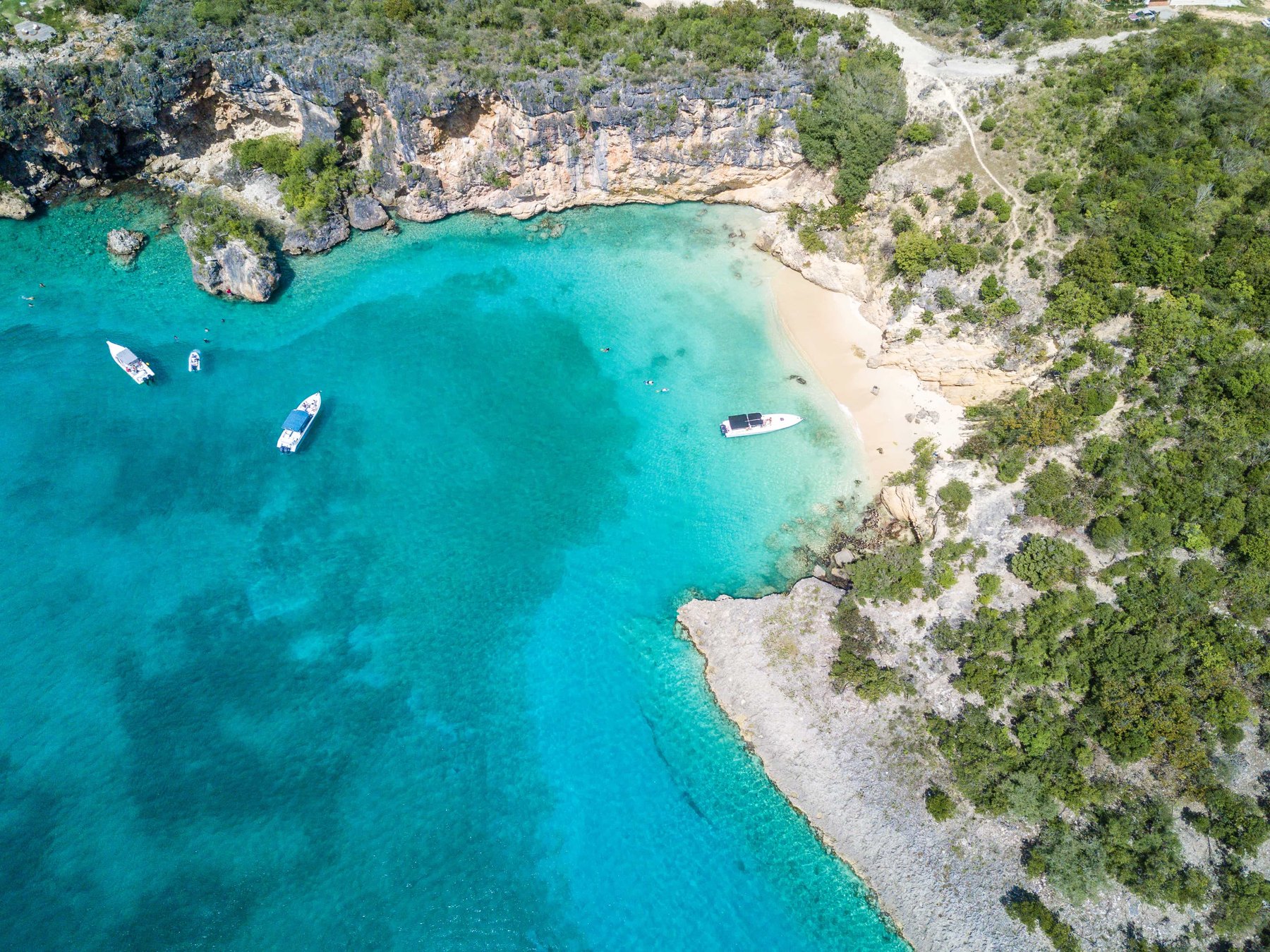 Aerial of Little Bay, Anguilla, small boats moored in turquoise water below limestone cliffs