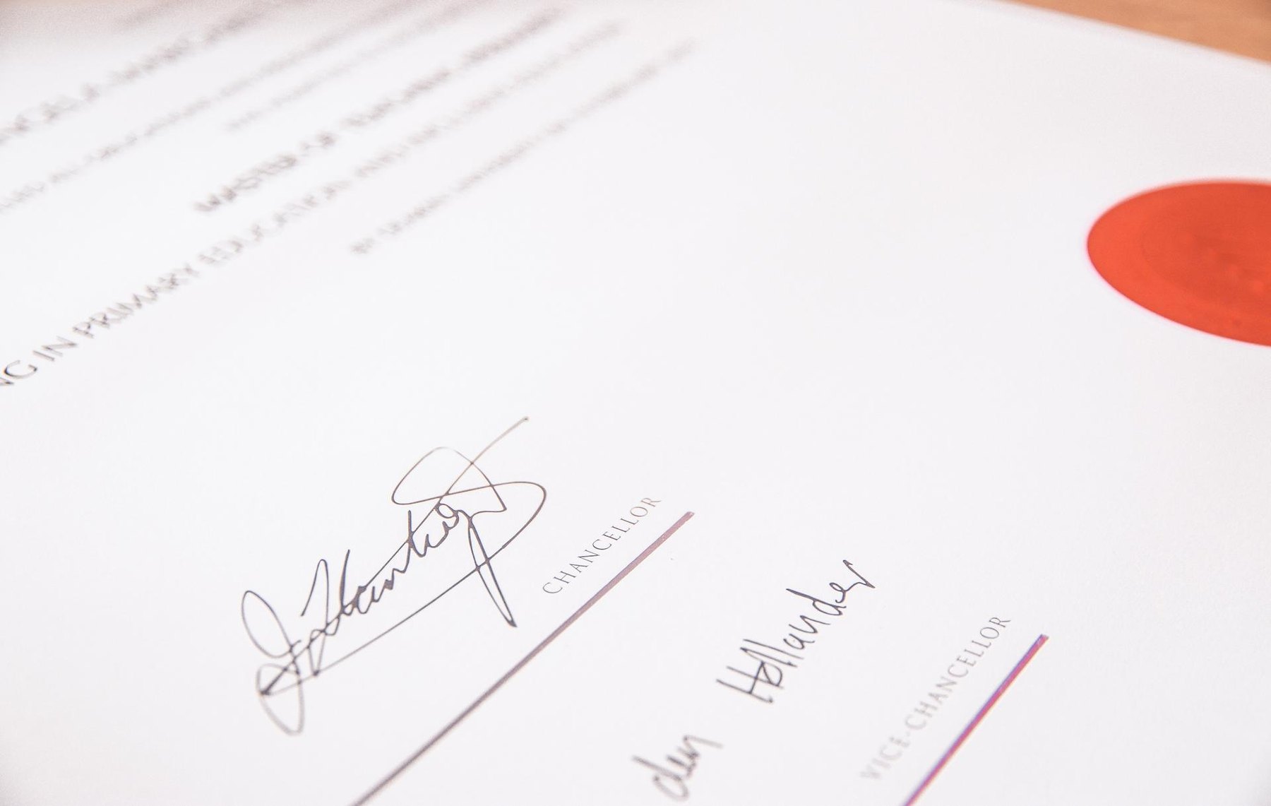 Close-up of a signed certificate showing signature lines and an embossed red wax seal