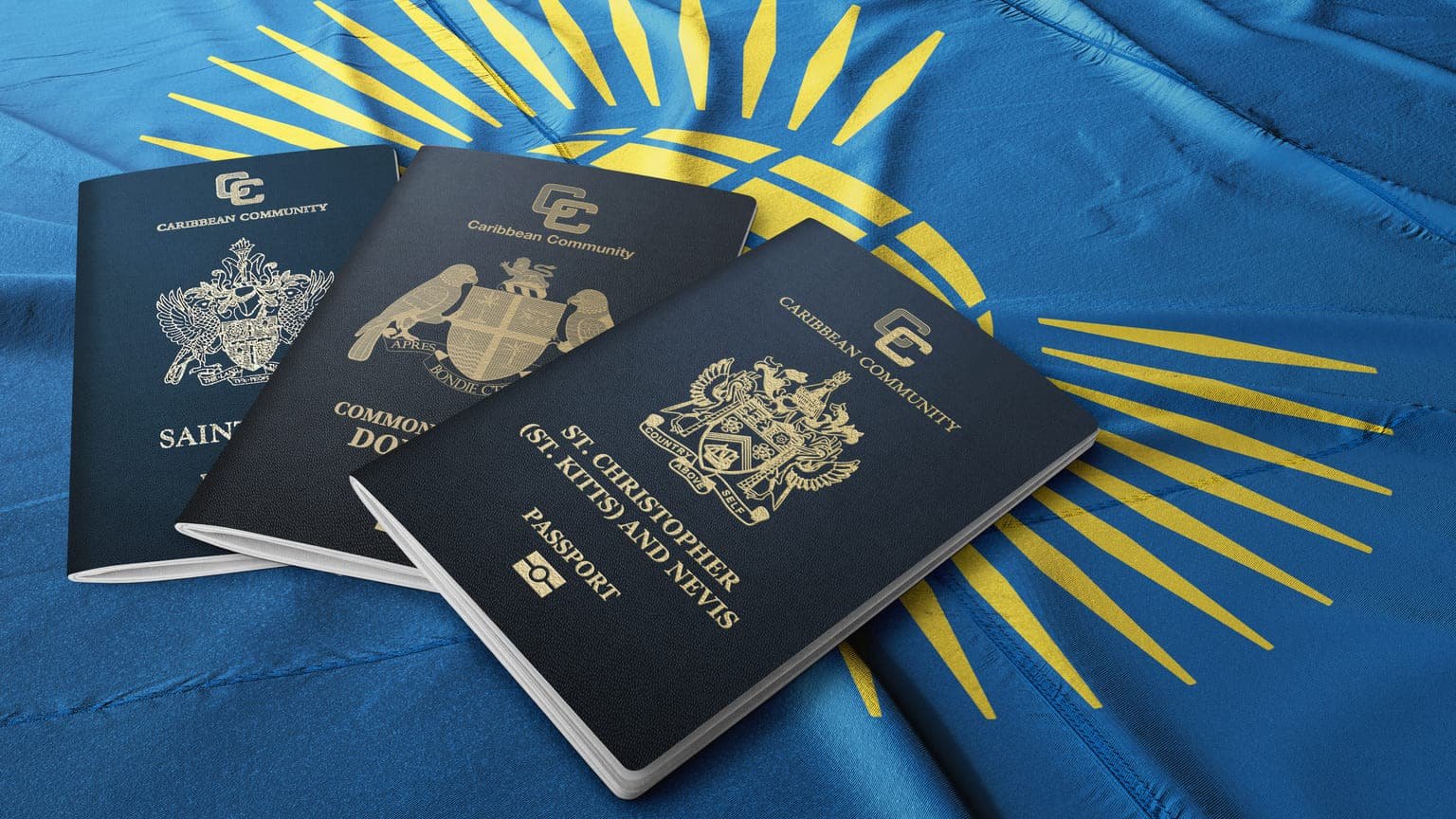 Three dark blue Caribbean Community passports arranged on a blue and yellow flag