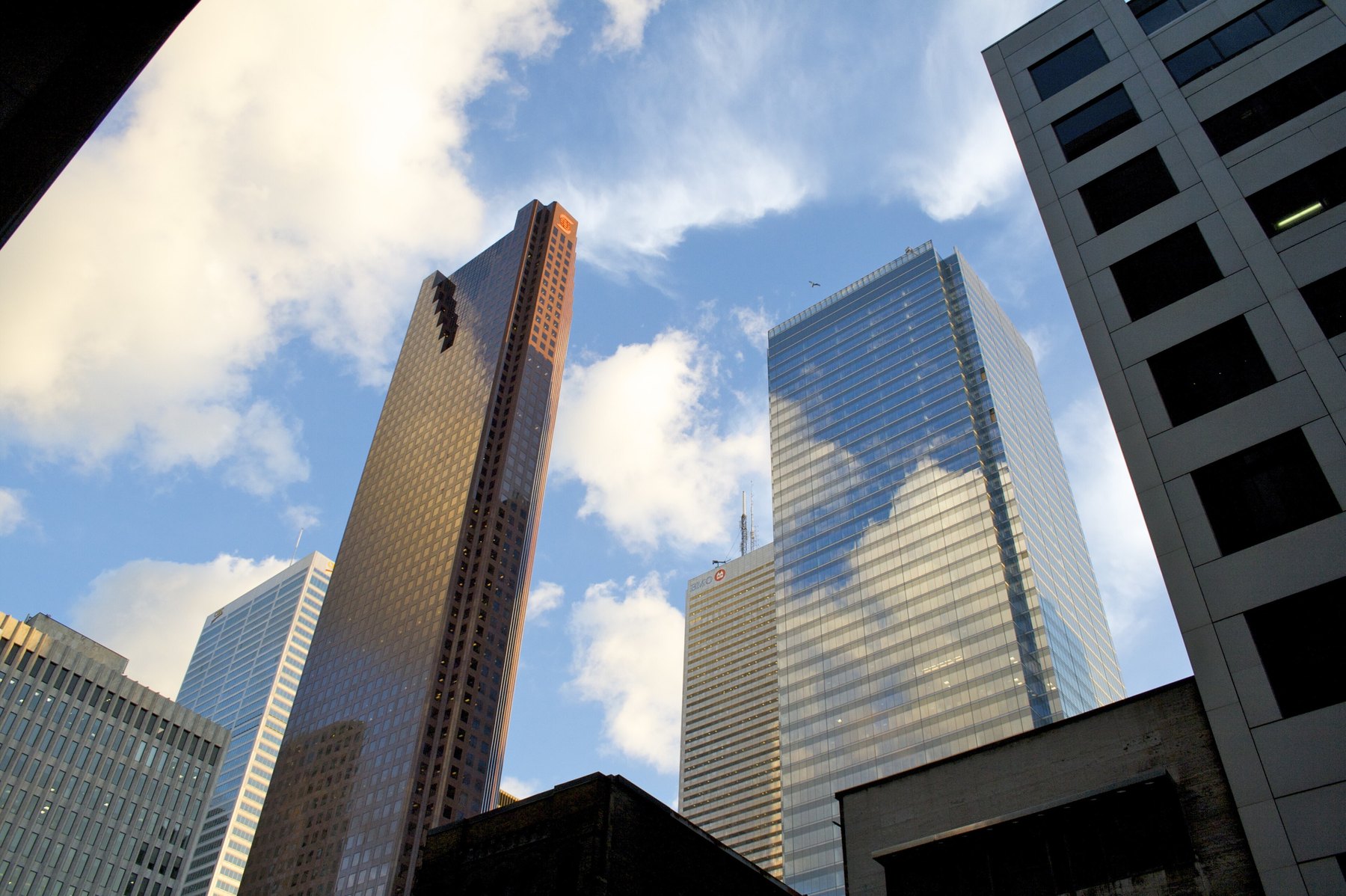 Downtown Toronto bank towers rising into a bright sky with scattered cloud