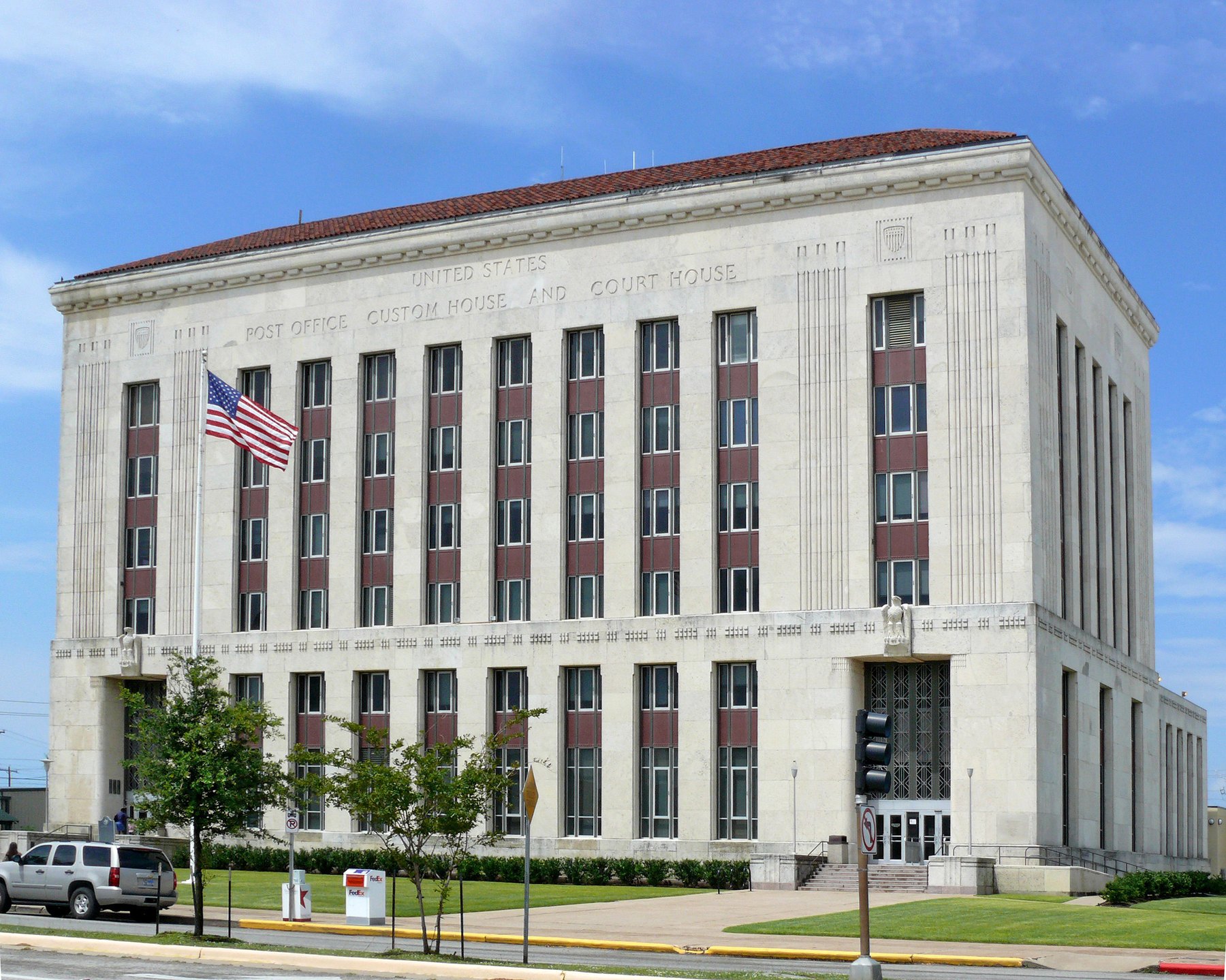 Limestone United States courthouse and custom house with American flag under blue sky