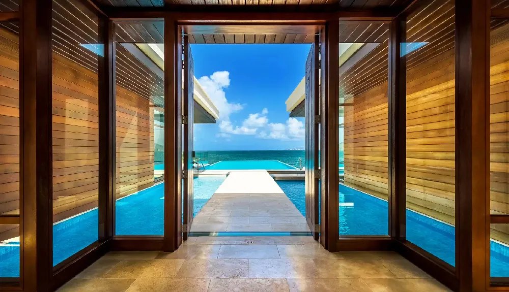View through open timber doors along a lap pool to the open sea