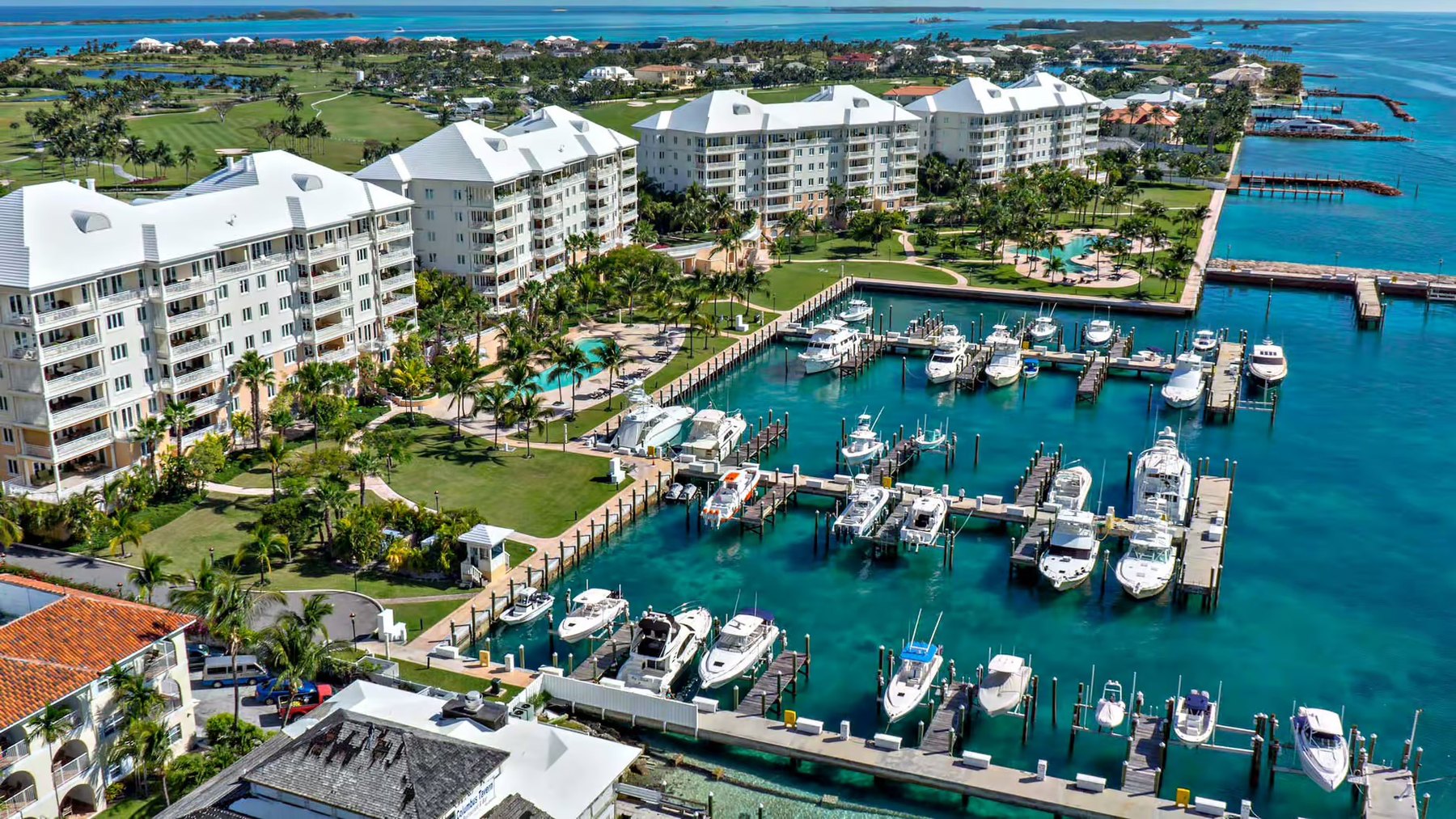 Aerial view of white waterfront apartment buildings beside a marina filled with motor boats