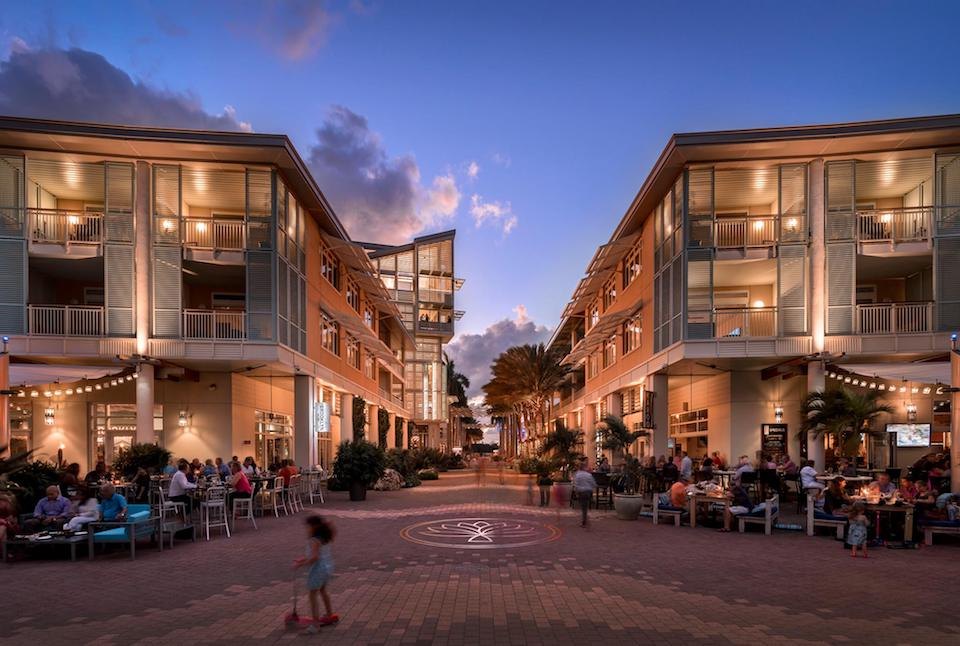Modern low-rise town square at dusk with lit cafes, string lights and diners outdoors