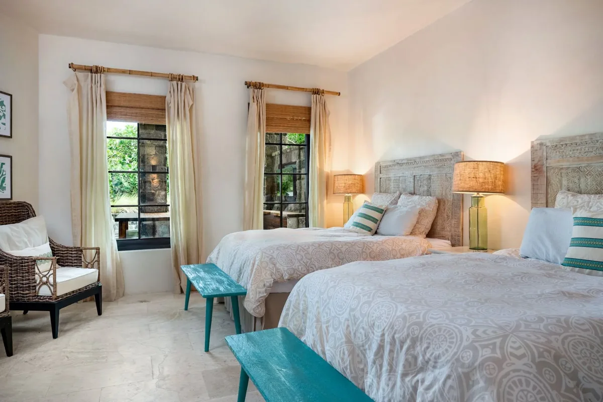 A twin bedroom with a teal bench