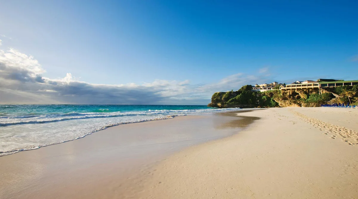 Crane Beach at ground level: empty pink-white sand and breaking surf filling the frame, the cliff and resort