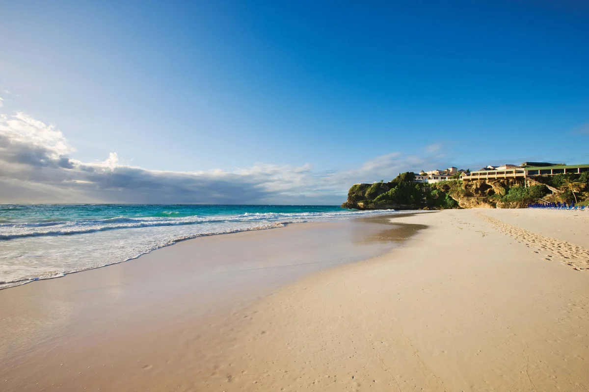 Crane Beach wide shot, empty sand and surf with the resort on the cliff at right — same scene as