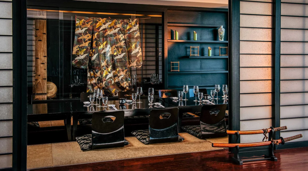 Zen restaurant seen from outside through shoji-style screens: dark timber and teal interior, patterned kimono