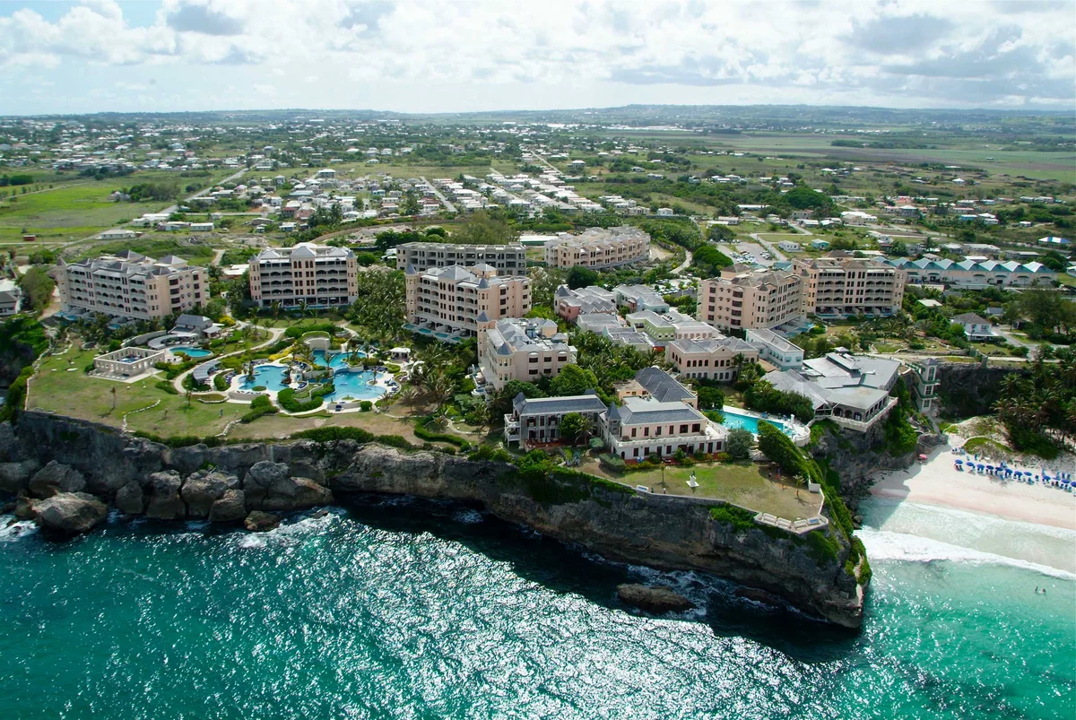 Aerial photo of the whole Crane resort on its clifftop: pink coral-stone residence blocks and pool complex on