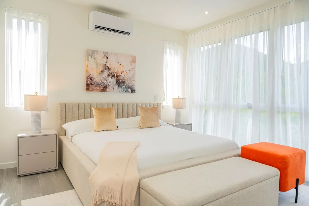 A bedroom with an orange ottoman