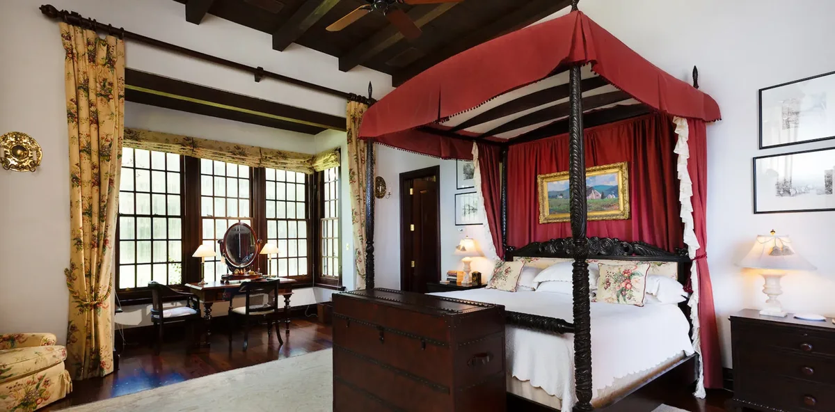 A four-poster bedroom with red drapes