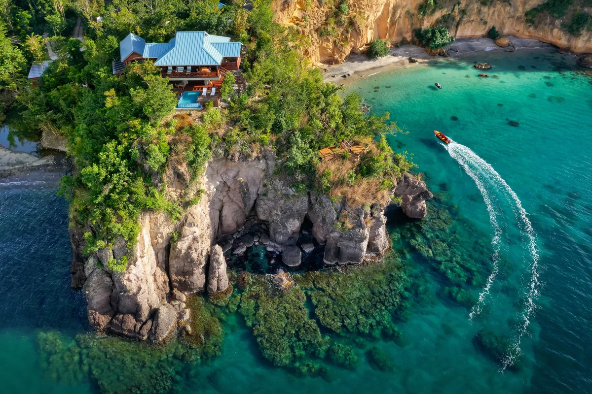 PHOTO β aerial of the Secret Bay headland and sea stack, speedboat cutting a wake through turquoise water.