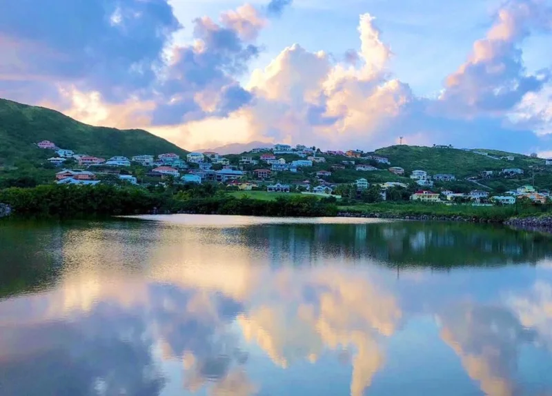 Lake beside the property at dusk looking across to pastel hillside homes; cloud reflections on the water.