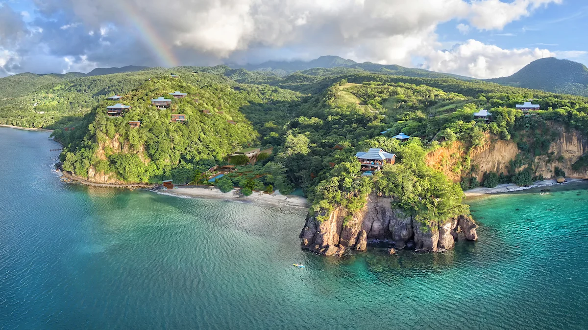 cOMPOSITE — real aerial photograph of the Secret Bay headland (rainbow, beach, sea stack) with CGI residences